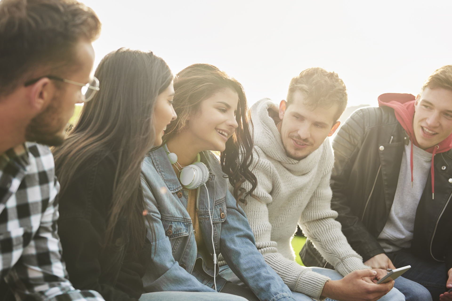 Drei junge Männer und zwei junge Frauen stehen beieinander, unterhalten sich lebhaft und haben sichtlich Spaß miteinander.