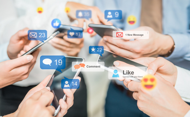 Mehrere Hände halten Smartphones, überlagert von Social-Media-Symbolen wie Likes, Nachrichten und Kommentaren.