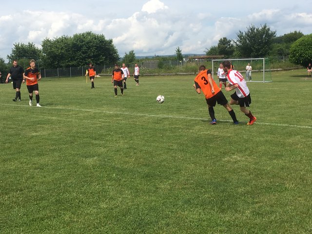 Mehrere Personen spielen Fußball auf einem Feld – sie tragen zwei verschiedene Trikots, um die Teams zu kennzeichnen.